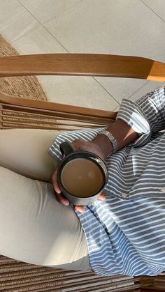 a woman sitting on a chair holding a cup of coffee