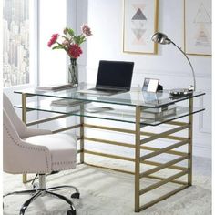 a glass desk with a laptop on it in front of a window and a chair