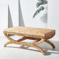 a wicker coffee table sitting on top of a white floor next to a palm tree