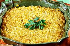 a casserole dish with parsley in it on a wooden tablecloth next to an orange napkin