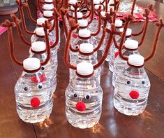 several plastic water bottles with faces and noses attached to them on a wooden table top