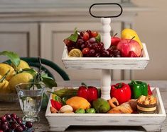 two tiered trays filled with fruit and vegetables on top of a wooden table