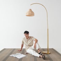 a man is sitting on the floor next to a lamp and paper in front of him