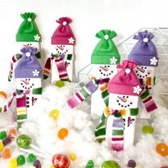 three snowmen made out of candy sitting on top of some cotton balls and gummy bears