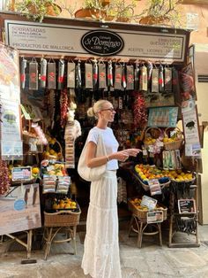 a woman standing in front of a fruit stand