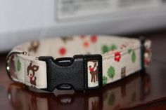 a white dog collar with brown and black dogs on it's side, sitting on a table