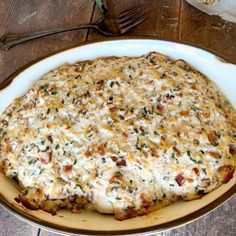 a casserole dish with cheese and other toppings sits on a wooden table