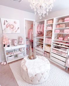 a white closet filled with lots of pink and white items on top of shelves next to a chandelier