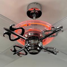 a ceiling fan that is lit up with red light and some black scissors hanging from it