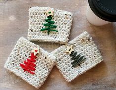 three crocheted coasters with christmas trees on them and a cup of coffee