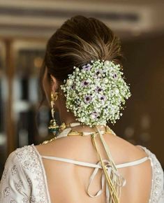 the back of a woman's head with flowers in her hair, wearing a white dress