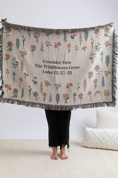 a woman holding up a blanket with flowers on it and the words consider how the wildflowers grow