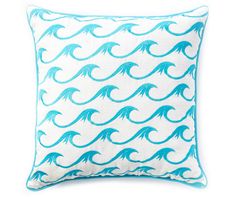 a blue and white pillow with an ocean wave design on the front, sitting against a white background