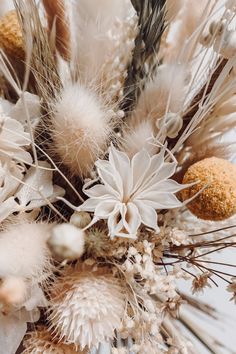 an arrangement of dried flowers and plants on a table