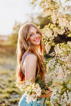 a beautiful young woman standing in front of flowers