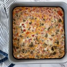 a casserole dish with meat and vegetables in it on a towel next to a bowl