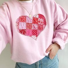 a woman wearing a pink sweater with a patchwork heart on it