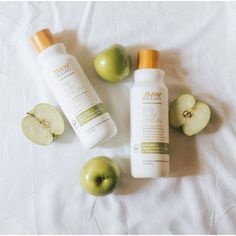 two bottles of shampoo, an apple and some other items on a white sheet