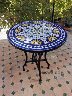 a blue and white table sitting on top of a tiled floor next to a tree