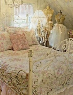 a bed with pink and white bedspread in a bedroom next to two mannequins