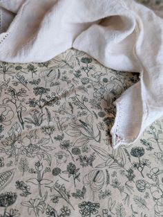 an unmade bed with white linens and flowers on the comforter, which has been folded over