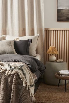 a bed sitting next to a table with a lamp on top of it