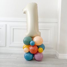 a number one balloon sitting on top of a pile of balloons in front of a white wall