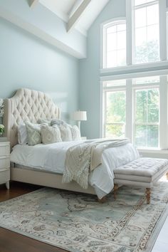 a bedroom with a large bed and two windows in it's center wall, along with a rug on the floor