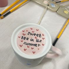 there is a cup with writing on it next to some pencils and markers in the background