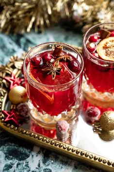 two glasses of cranberry punch on a tray with christmas decorations in the background