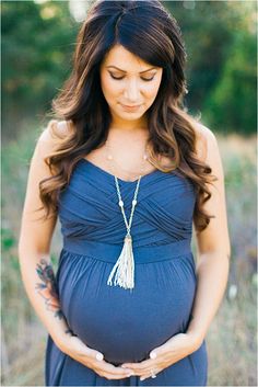 a pregnant woman in a blue dress holding her belly