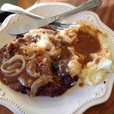 a white plate topped with mashed potatoes and gravy next to a fork