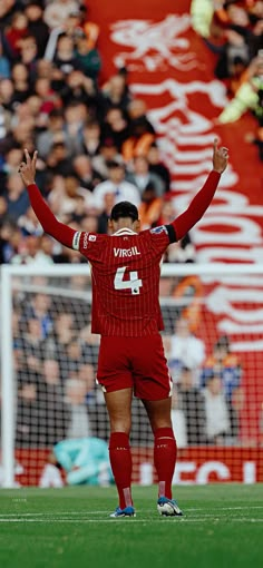 a soccer player with his hands up in the air while standing on top of a field