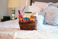 a basket filled with wine and snacks on top of a bed