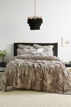 an elephant print comforter on a bed in a white room with a chandelier hanging from the ceiling