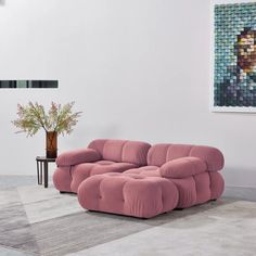 a pink couch sitting on top of a rug next to a vase filled with flowers