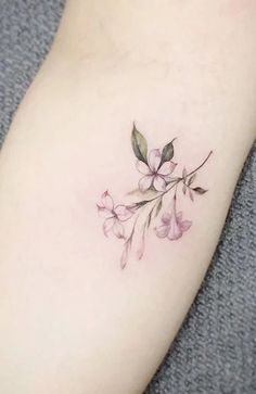 a small flower tattoo on the right arm and leg, with pink flowers growing out of it