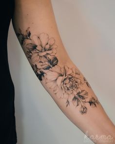 a woman's arm with black and white flowers on the left side of her arm