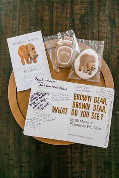 some brown bears are sitting on a wooden table with cards and magnets in front of them