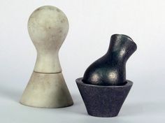 two ceramic sculptures sitting next to each other on a white surface, one is black and the other is gray