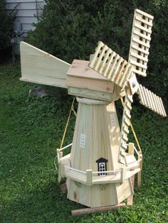 a wooden windmill sitting on top of a lush green field