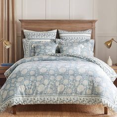 a bed with blue and white comforter in a bedroom next to two lamps on either side of the bed