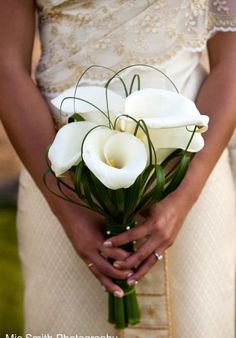 a woman holding a bouquet of white flowers in her hands and wearing a wedding dress