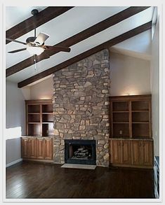 an empty living room with wood flooring and stone fireplace