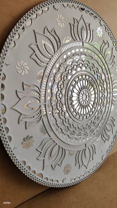 a decorative glass plate sitting on top of a cardboard box next to a brown wall