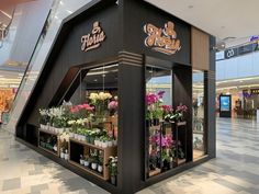 the inside of a flower shop with lots of flowers and plants on display in it