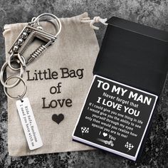 a keychain with a note attached to it sitting next to a bag that says,'to my man never forget that i love you '