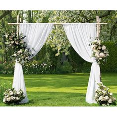 an outdoor wedding set up with white drapes and floral arrangements on the grass area