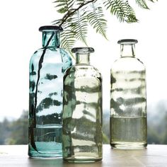 three glass bottles sitting on top of a table