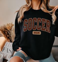 We are working hard to get all orders processed quickly, but shipping services are currently experiencing high demand and delays. Because of this, we cannot guarantee that your order will arrive before Christmas. While we are doing everything we can in our end, we are dependent on shipping companies to deliver on time .Are you looking for Soccer mom Sweatshirt ? We got you! ✅ ABOUT OUR Soccer Mama Tshirt ▸  These garments are made from polyester and cotton.  ▸ The collar is ribbed knit, so it re Soccer Mama Shirt, Sport Mom, Soccer Tees, Mama Tshirts, Mom Hoodies, Soccer Mom, Soccer Shirts, Mom Sweatshirt, Mama Shirt